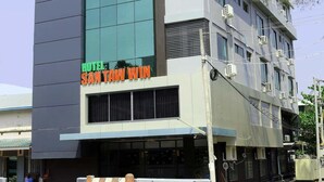 Ein mehrstöckiges Hotel im modernen Stil, mit großen Fenstern und einem gut sichtbaren Schild für "HOTEL SANTAW WIN".