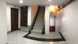 Ein Korridor mit Marmorboden, einer Holztür, einer Treppe und einem roten Schrank.