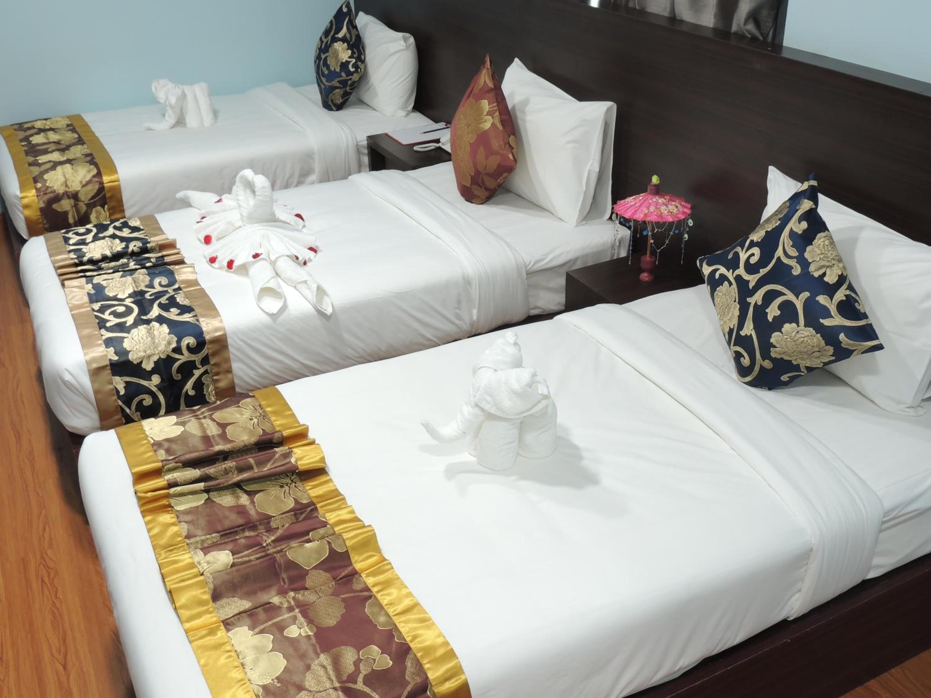 Une chambre d’hôtel avec deux lits simples, chacun étant agrémenté d’une couvre-lit blanche et de coussins décoratifs.
