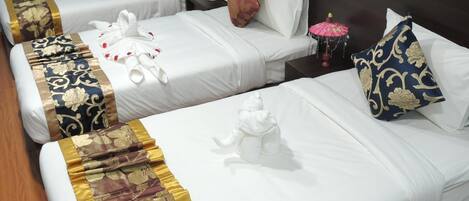 A hotel room with two single beds, each with a white bedspread and decorative pillows.