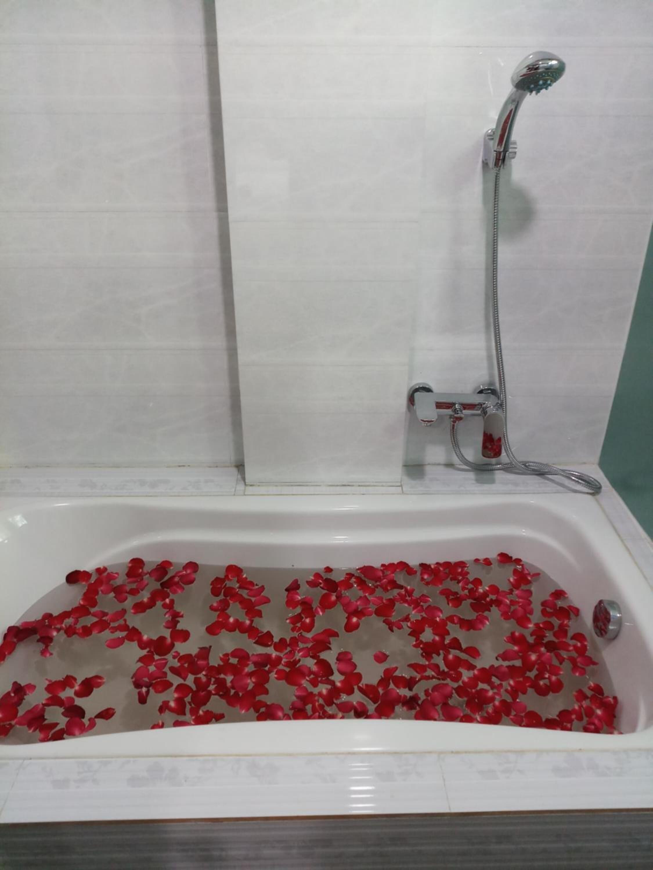 Una bañera llena de agua y pétalos de rosa.