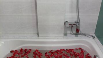 Una bañera llena de agua y pétalos de rosa.