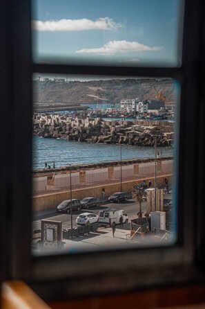 A coastal view with a harbor, parked cars, and a pedestrian walkway. - Riad Le Cheval Blanc (Safi)