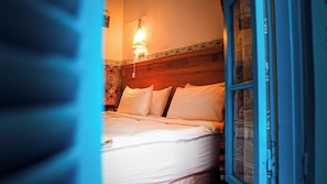 A bed with white linens, a wall-mounted lamp, and a decorative border.