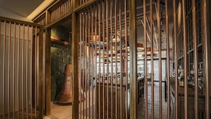 A room with a large, ornate door and a view of a bar area with shelves of bottles and glasses. - Wave Resort – Ultra All Inclusive (Pomorie)