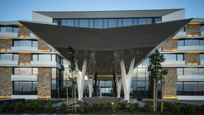 A modern building with a unique roof structure, large windows, and a central courtyard with a water feature.