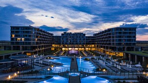 A hotel with a central pool, multiple balconies, and outdoor seating areas.
