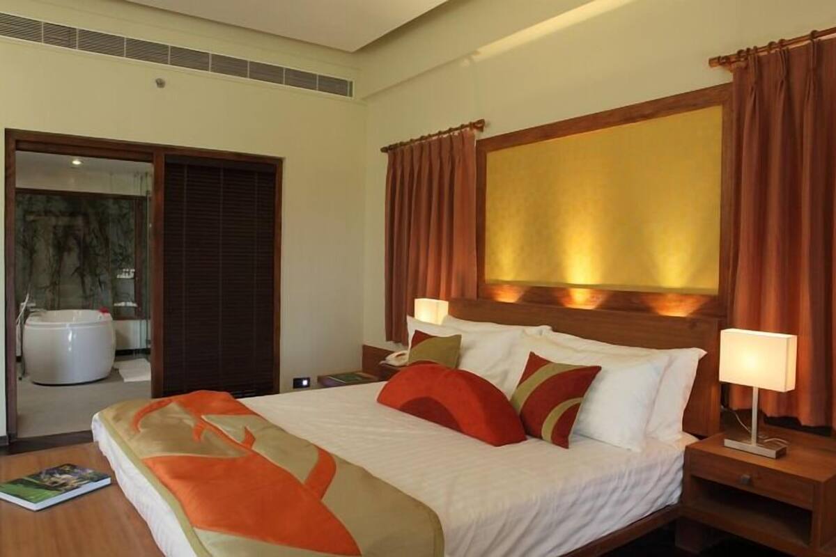 A hotel room with a large bed, a wooden headboard, and a bathroom with a bathtub.