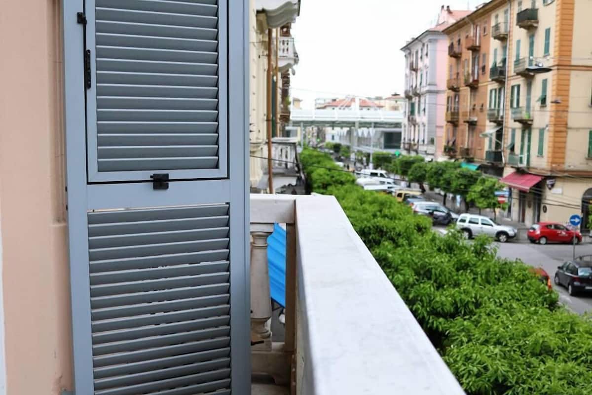 A balcony with a view of a street lined with parked cars and buildings.