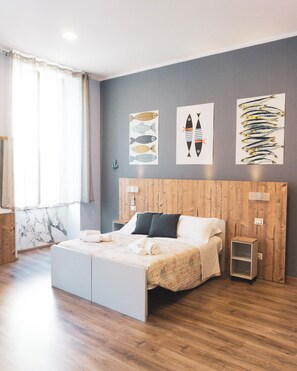A modern bedroom with a wooden headboard, a bed with white bedding, and artwork on the walls. - I Sapori Del Levante (La Spezia)