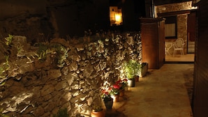 A stone wall with potted plants and a doorway leading to a lit interior. - Casas Rurales Abuela Benita (Cebreros)