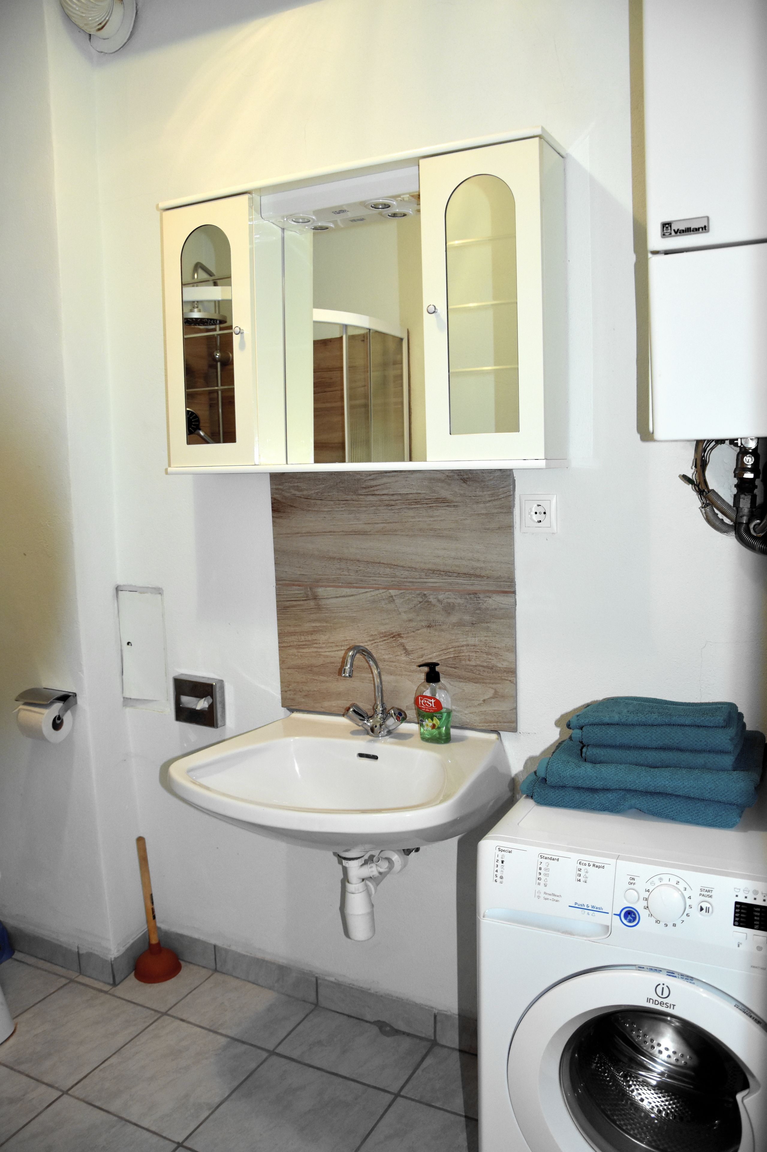 A bathroom with a sink, mirror, and washing machine.