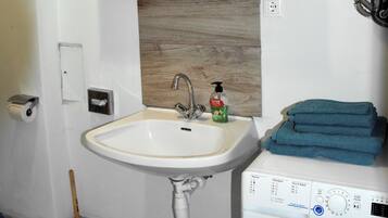 A bathroom with a sink, mirror, and washing machine.