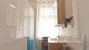 Un baño moderno con cabina de ducha de vidrio, tocador de madera y perchero.