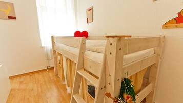 Habitación con literas, una escalera, ventana con cortinas y un cuadro con un estante pequeño en la pared.