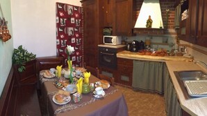 Een kleine keuken met een eethoek, voorzien van een magnetron, oven, spoelbak en een tafel gedekt met borden en bestek.