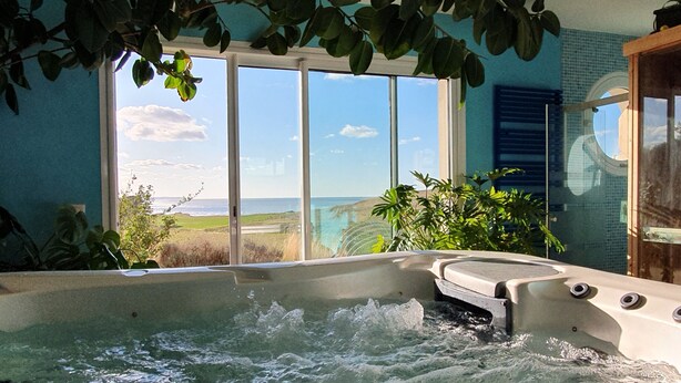Un jacuzzi con vista al océano a través de amplias ventanas.