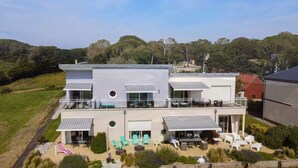 Una casa moderna de dos pisos con balcón, mobiliario exterior y jardín ajardinado.