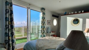 Un dormitorio con una cama grande, una mesita de noche, una lámpara, un espejo y vistas al exterior.