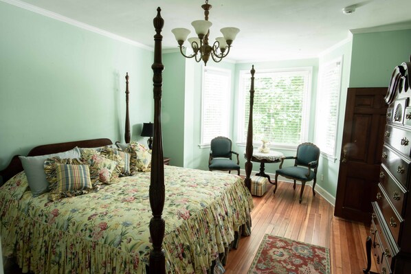 A bedroom with a four-poster bed, a chandelier, two chairs, a dresser, and a window with blinds. - Valparaiso Inn Bed & Breakfast (Valparaiso)