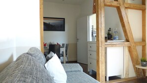 Uma sala de estar moderna com um sofá cinza, uma escada de madeira, um espaço de jantar e uma bancada de cozinha.