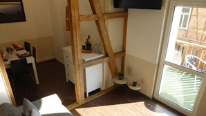 Uma sala de estar aconchegante com uma cama beliche de madeira, um espaço de refeições com mesa e cadeiras brancas, e uma grande janela com vista para o exterior.