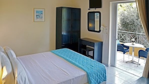Habitación de hotel con cama, escritorio, silla y balcón con mesa y sillas.