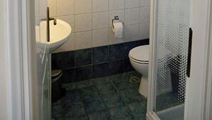 Un baño con inodoro, lavabo y cabina de ducha con mampara de vidrio.