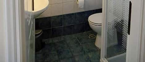 A bathroom with a toilet, sink, and a glass-enclosed shower area.