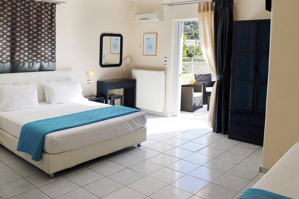 A hotel room with a bed, a desk, a chair, and a view of the outside.