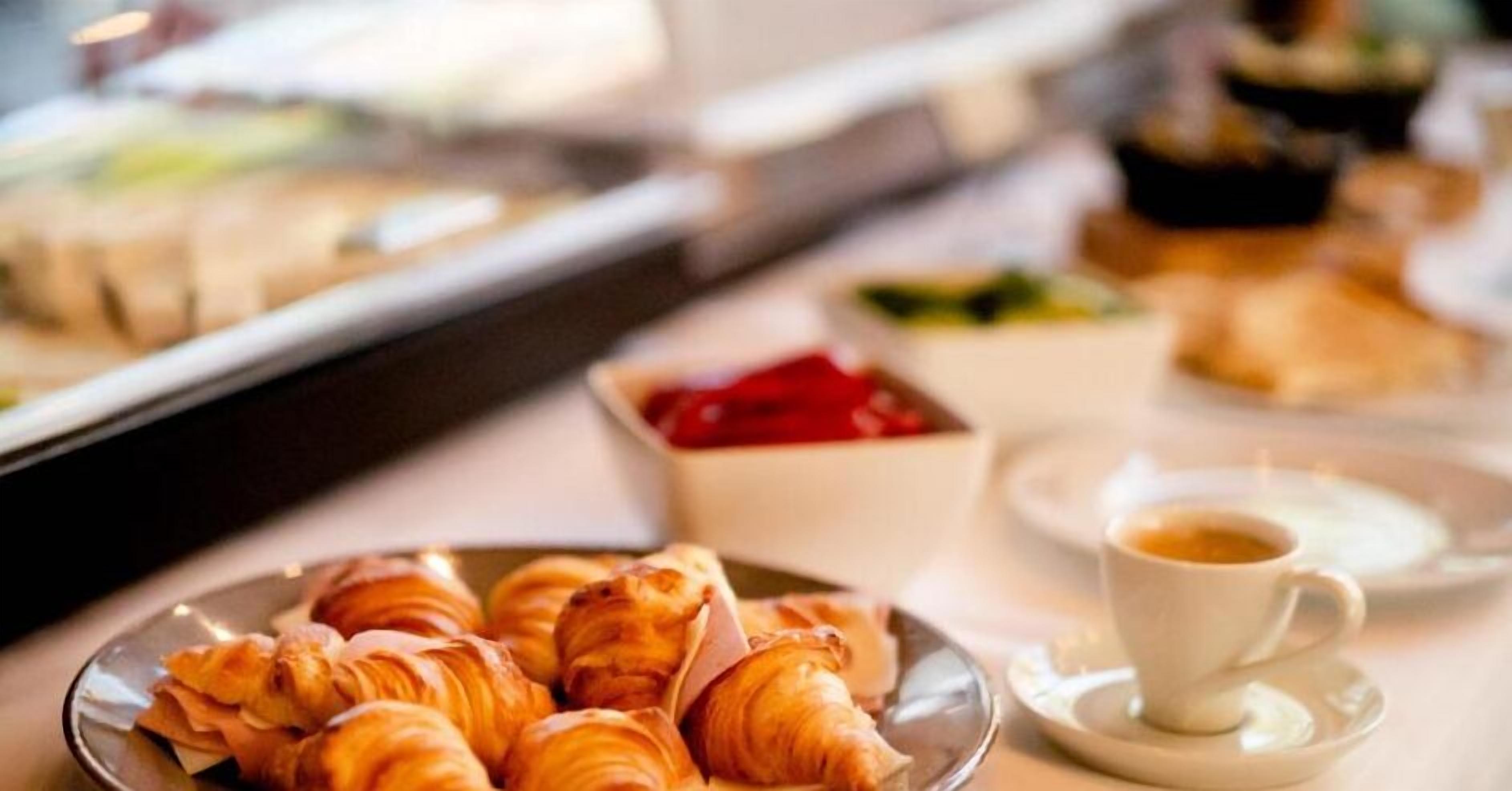 Une table dressée pour le petit-déjeuner avec des croissants, une tasse de café et divers autres plats.
