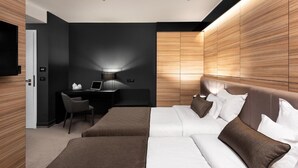 Una habitación de hotel moderna con cama, mesitas de noche, un escritorio y una silla.