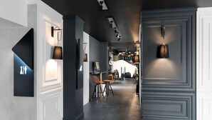 Un pasillo moderno con techo oscuro, iluminación empotrada y una puerta blanca al final.