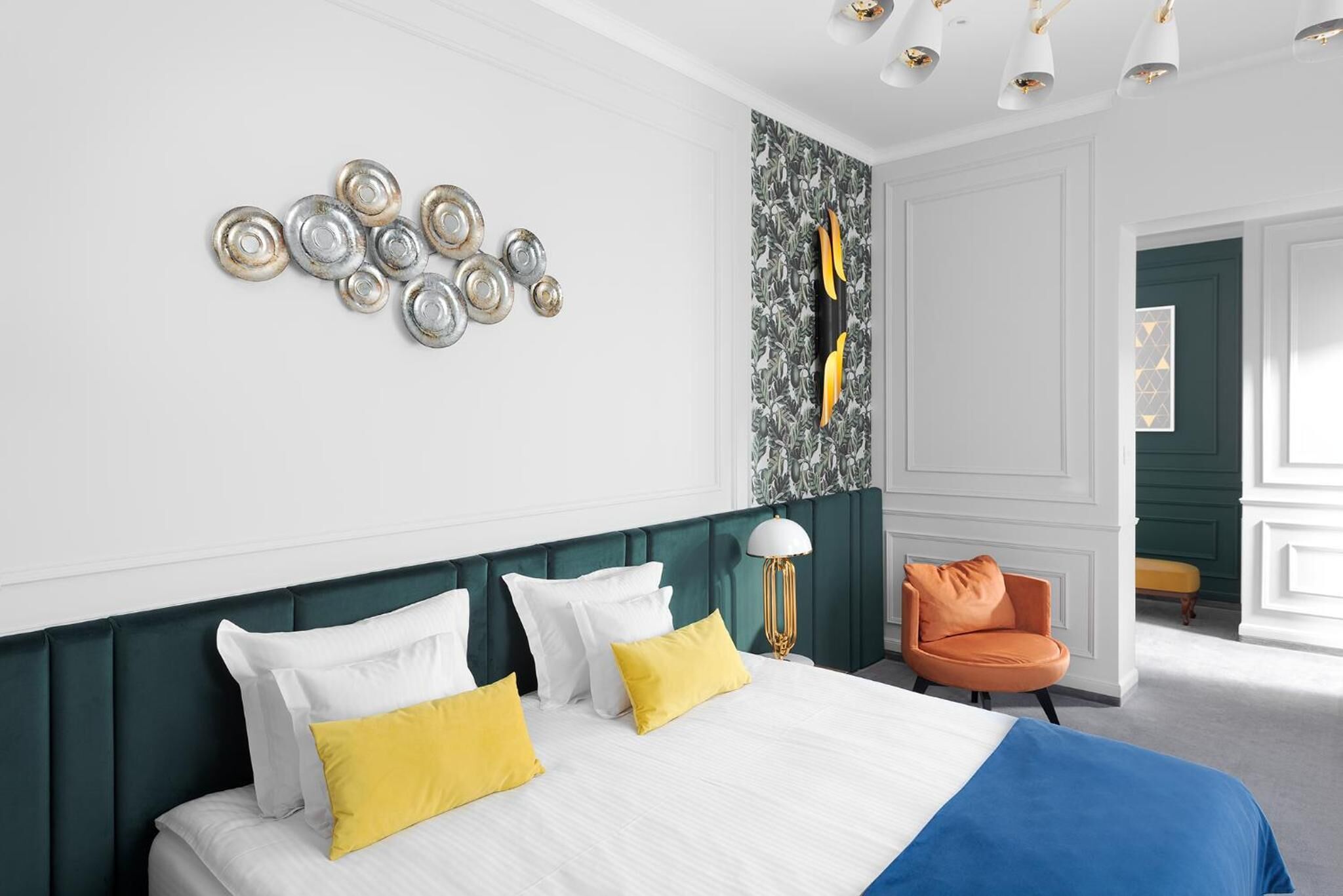 A hotel room with a bed, a chair, and a wall with decorative plates.