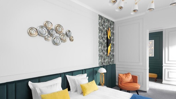 Habitación de hotel con cama, una silla y una pared decorada con platos.
