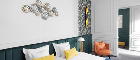 A hotel room with a bed, a chair, and a wall with decorative plates.