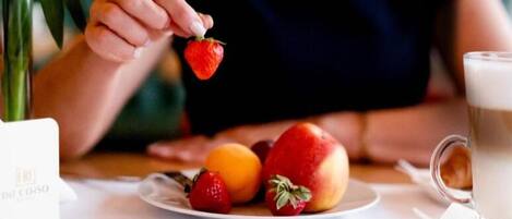 Un plato con fresas, melocotones y una naranja sobre una mesa.