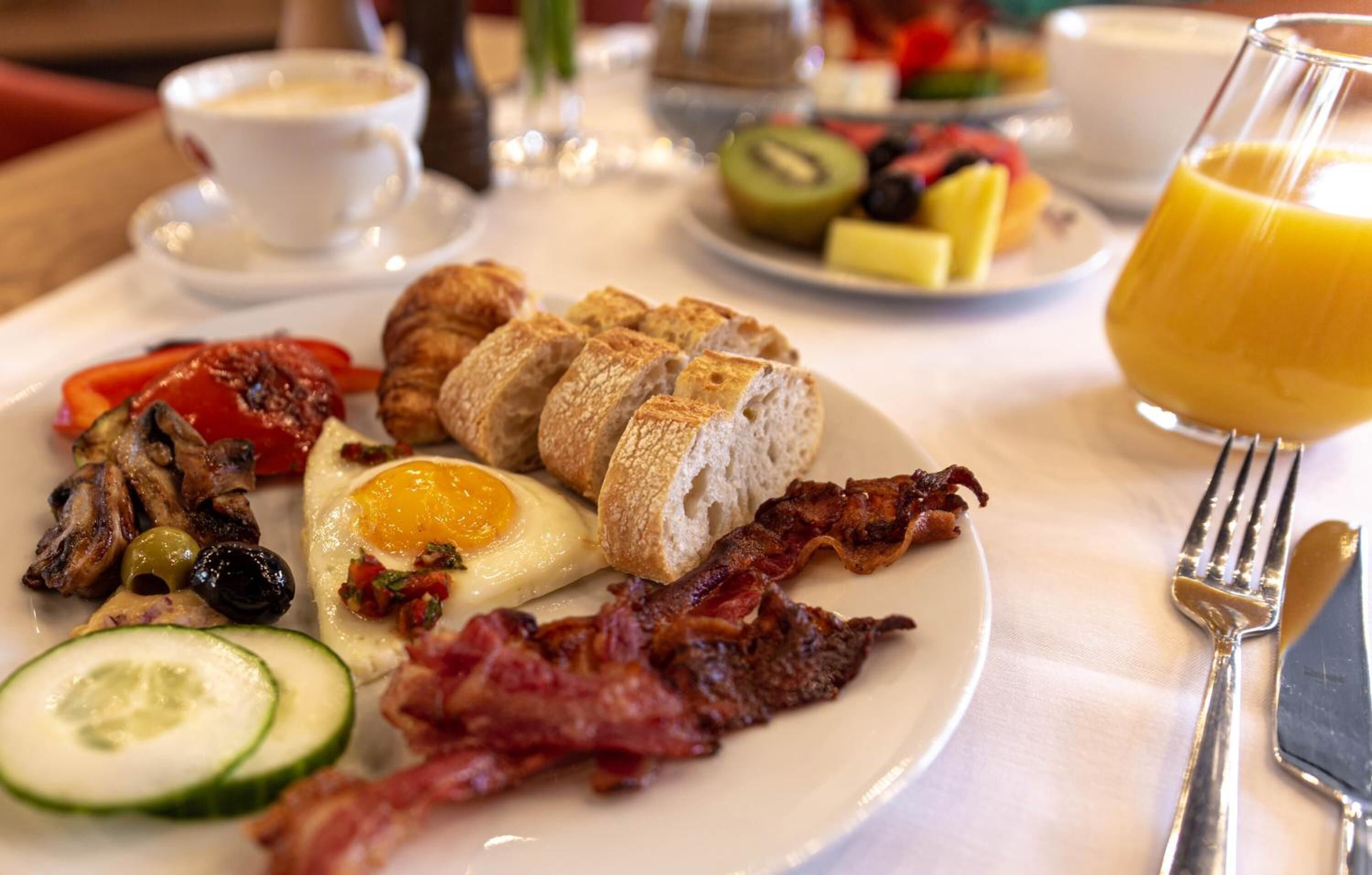 A breakfast plate with eggs, bacon, toast, and vegetables.