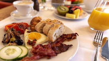 A breakfast plate with eggs, bacon, toast, and vegetables.