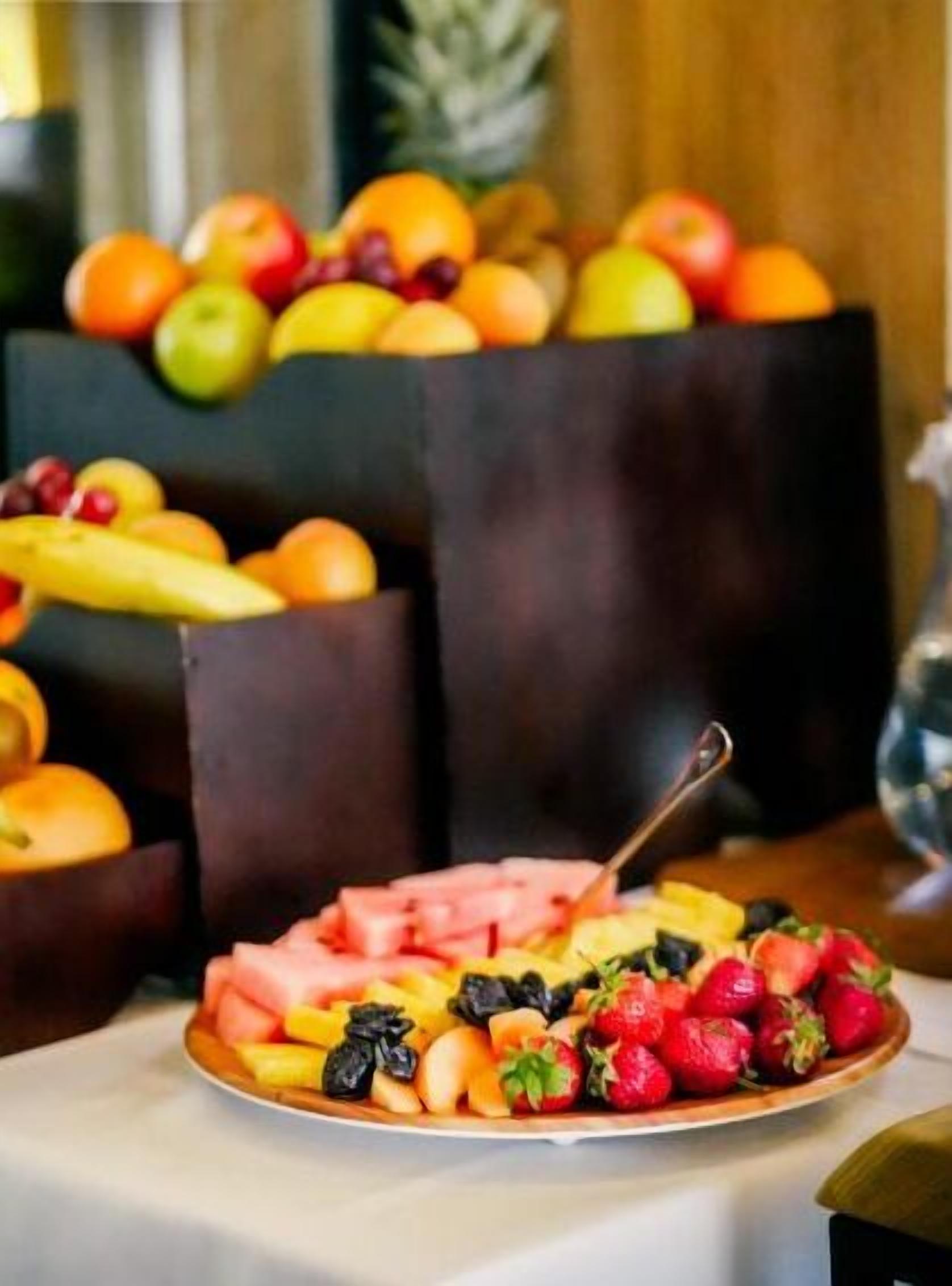 Eine Obstplatte mit verschiedenen Früchten und einem Löffel auf einem Tisch.
