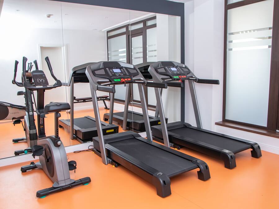 Un gimnasio con cintas de correr, elípticas y una bicicleta estática.
