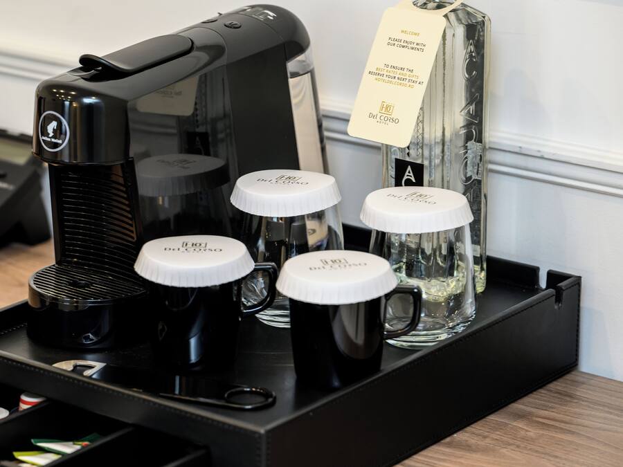 A coffee machine with four black coffee cups and a glass carafe on a tray.