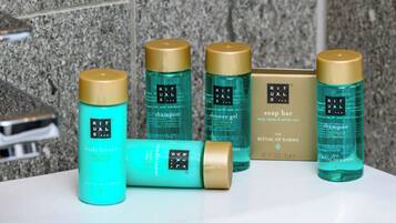 A bathroom with a granite countertop and various Ritual of Karma personal care products.