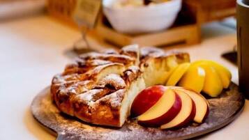Un bufé de desayuno con diversos pasteles, frutas y una cafetera.