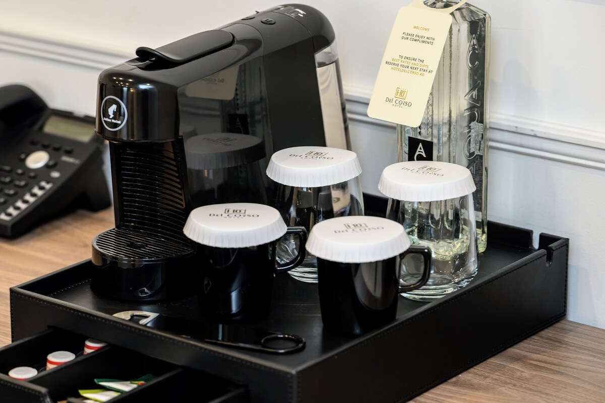 A coffee machine with four black coffee cups and a glass carafe on a tray.