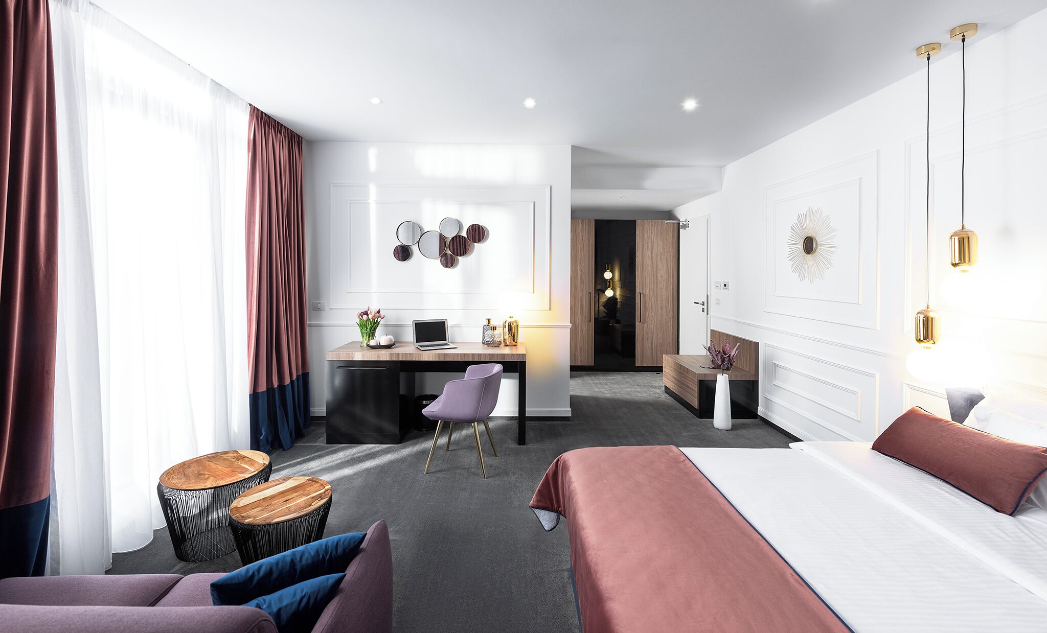 A modern hotel room with a bed, a desk, a chair, and a small table.