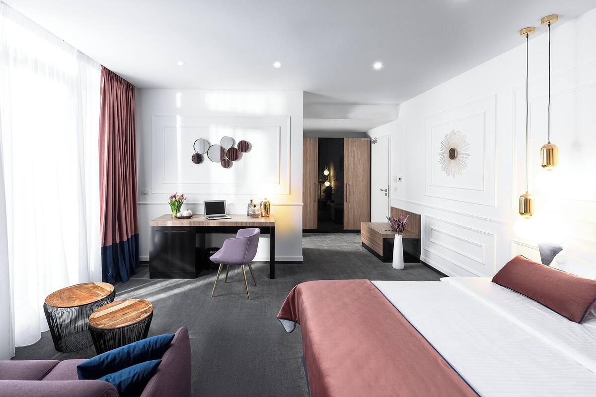 Una habitación de hotel moderna con una cama, un escritorio, una silla y una pequeña mesa redonda.