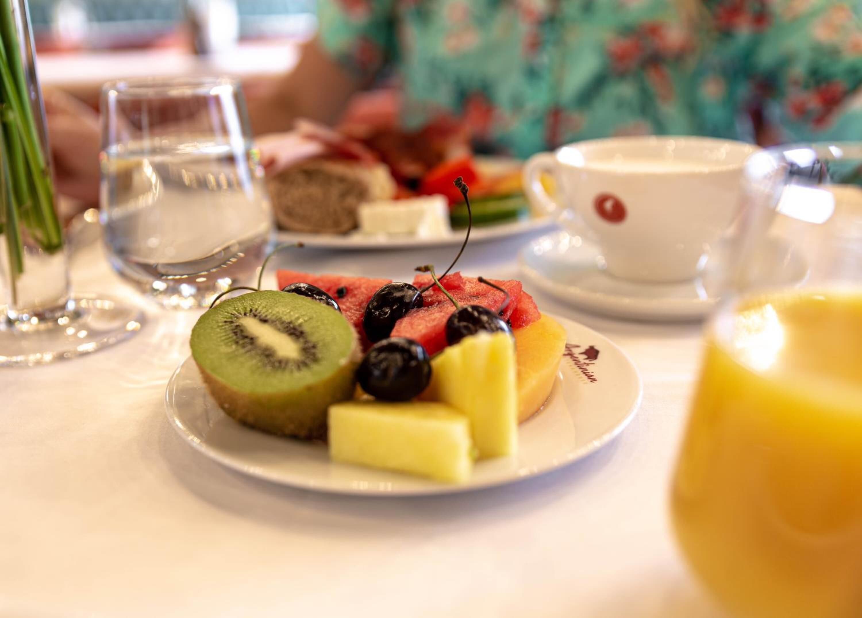 A table with a plate of fruit, a cup of coffee, and a glass of water.