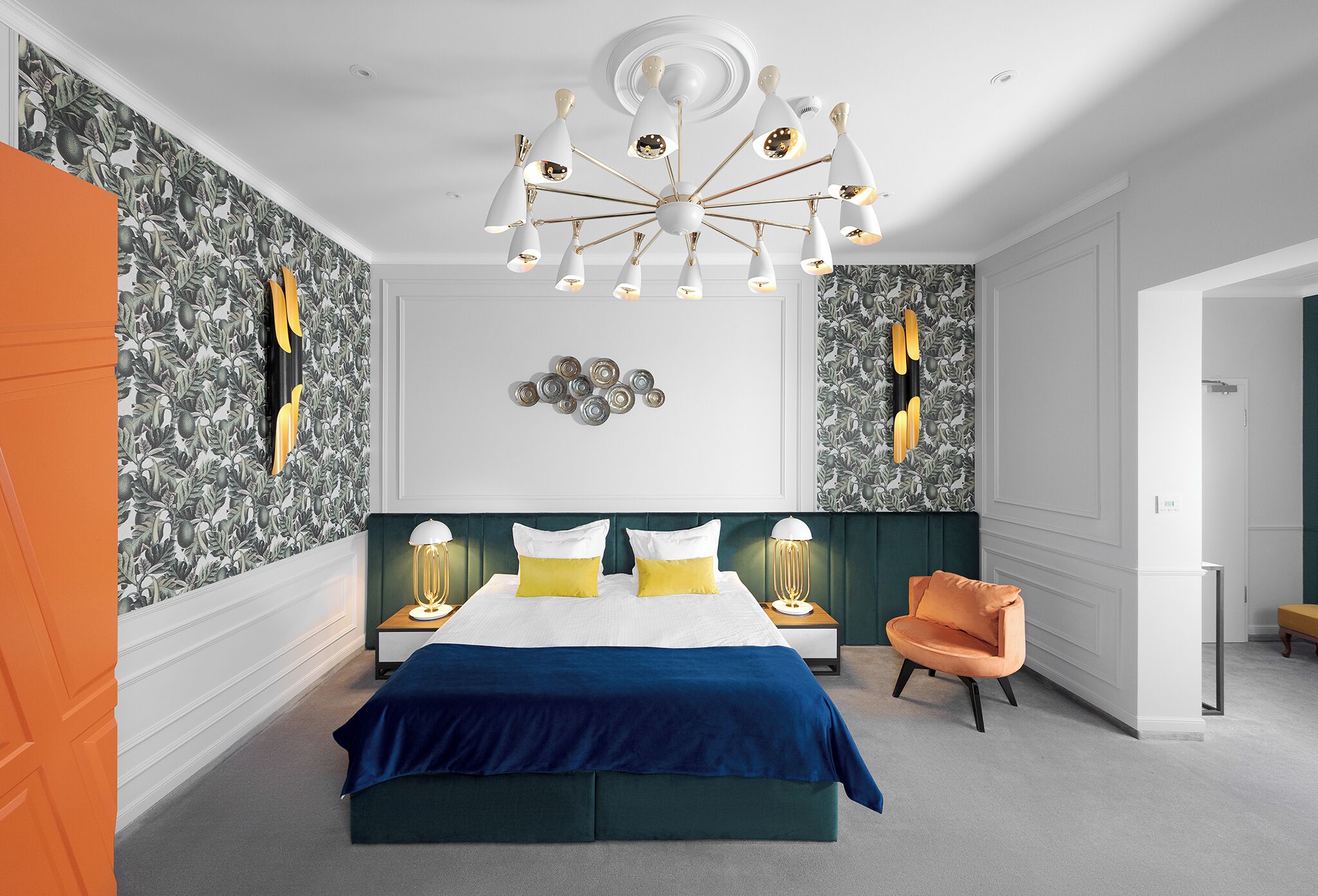 A bedroom with a large bed, a modern chandelier, and a green accent wall.