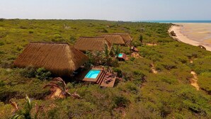 A resort with thatched-roof huts, a swimming pool, and a beach view. - asDunas Lodge (Vilanculos)
